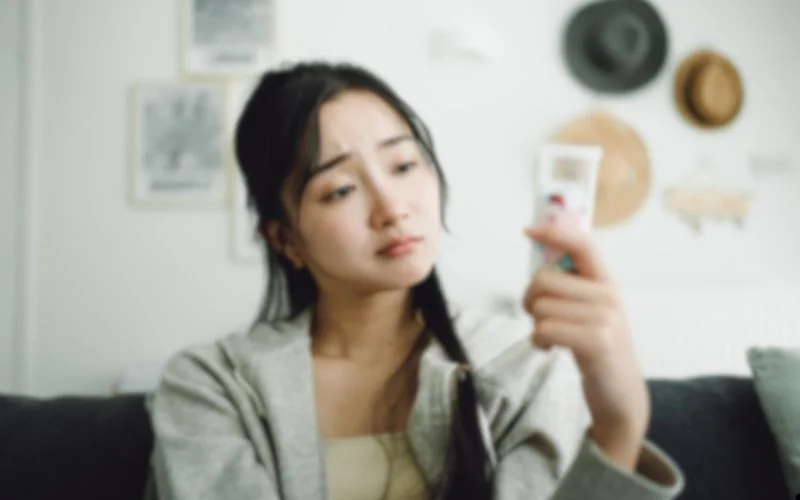 A-women-sitting-on-a-couch-looking-at-their-cell-phone